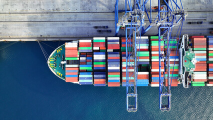 Aerial top down photo of industrial cargo container ship being loaded by large cranes in logistics...