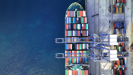 Aerial top down photo of industrial cargo container ship being loaded by large cranes in logistics...