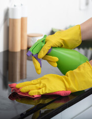 Close up shot of female hands holding bottle spray and rag for cleaning the stove	