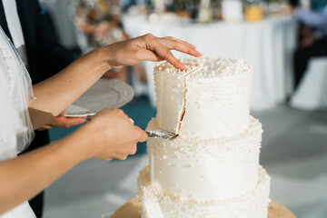 bride removes the first piece of wedding cake with her hands