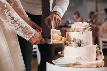 Newlyweds take off the first cut piece of the wedding cake - obrazy, fototapety, plakaty
