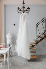 white wedding dress hanging in a bright interior