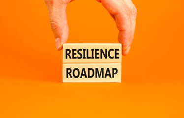 Resilience roadmap symbol. Concept word Resilience roadmap typed on wooden blocks. Beautiful orange table orange background. Businessman hand. Business and resilience roadmap concept. Copy space.