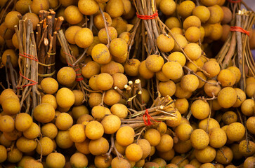 Longan fruit close-up as a background. The Dragon Eye Harvest is in a pile on the counter. Fresh tropical fruits. Dimocarpus longan, Central Thailand