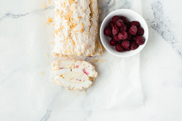 Cut of homemade meringue roll decorated with almond flakes and freeze-dried red berries on the...