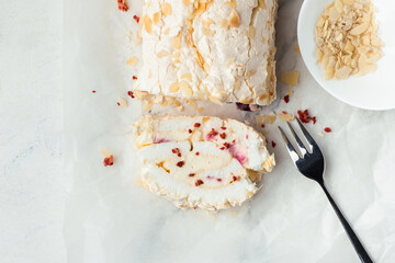 Cut of homemade meringue roll decorated with almond flakes and freeze-dried red berries on the...