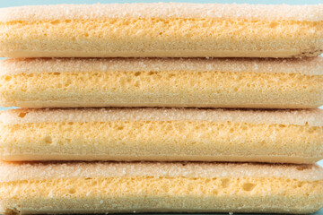 Traditional Italian savoiardi ladyfinger cookies stacked together as a textured background. Macro shot of sweet sponge biscuits for tiramisu cake.