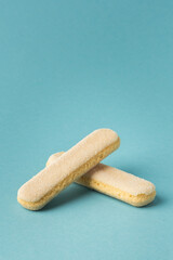 Traditional Italian savoiardi ladyfinger cookies stacked together on a blue pastel background. A pile of sweet sponge biscuits for tiramisu cake