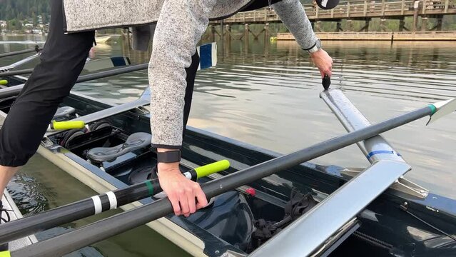 female coach showing students how to get into the boat for rowing and how to screw on the spring she unscrews the screw before putting her foot into the boat lifts the other keeping balance