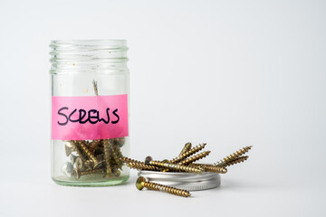 jar of woodworking screws with the screw top off and filled with screws isolated on a white background