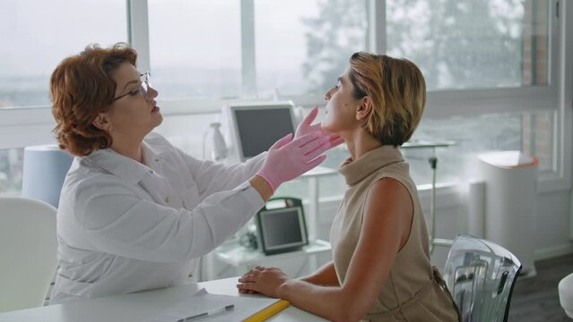 Dermatologist touching woman face examining skin in modern cosmetology clinic.