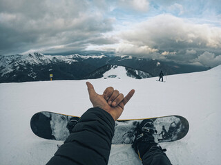 Point of view of man in waves hallo sign with hand relaxing sitting on the snow in ski facilites...