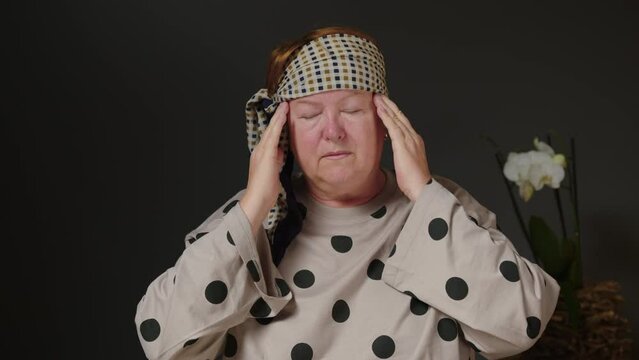 An elderly woman is experiencing headaches and depression. Poor health in old people. The concept of diseases of the elderly