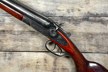 Old Vintage Classic trigger double-barreled hunting rifle on a wooden background. Smooth-bore hunting rifle.