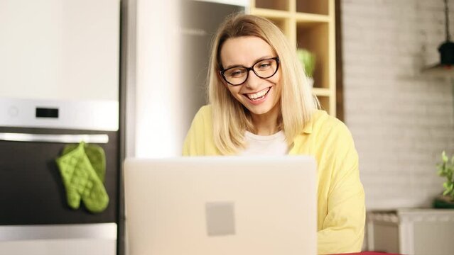 Portrait of beautiful young blond woman with glasses has video call conference meeting interview by laptop computer at home apartment Smiling lady talking on working or personal conversation