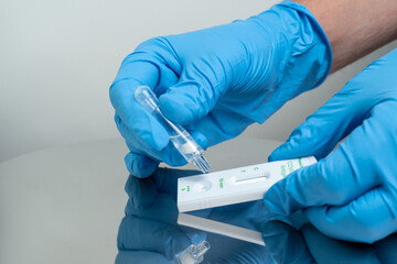 Person drops specimen test liquid in rapid test cassette for detection of Corona virus Covid-19....