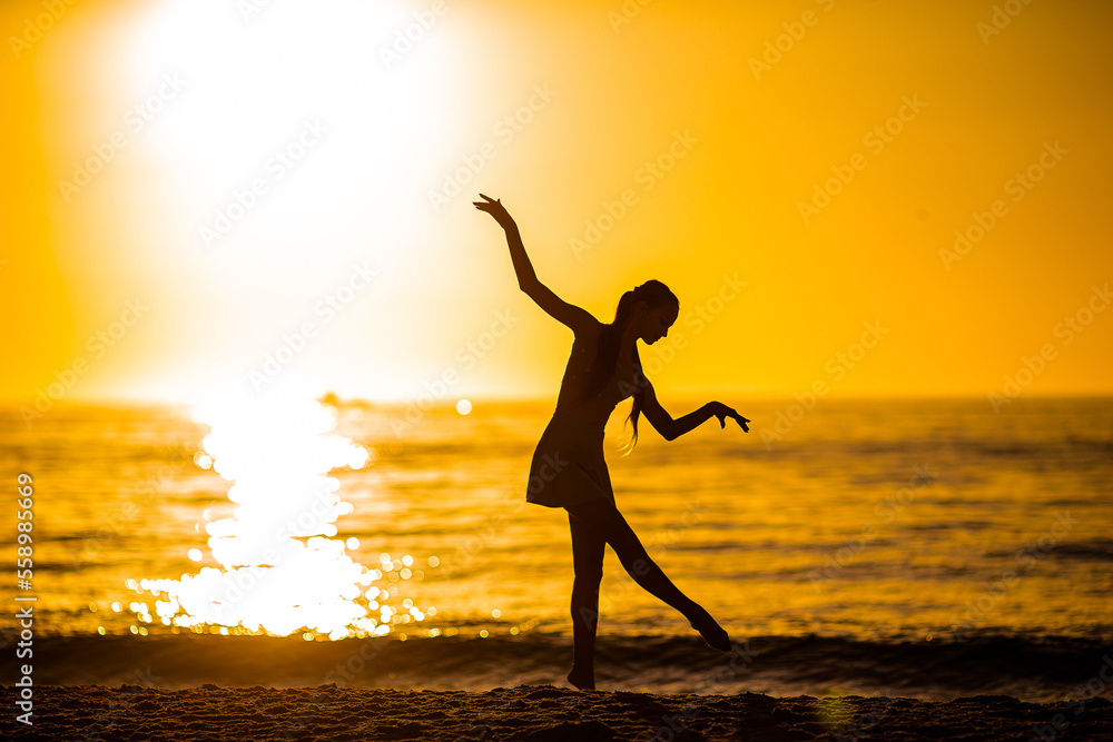 Wall mural Silhouette of the beautiful girl dancing on the beach at sunset