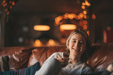 Portrait of candid authentic smiling boy teenager having fun emotion at wooden lodge Xmas decorated