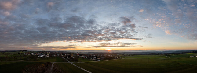 sunrise with colorful clouds above Dürrenmettstetten village in swabia germany with haze in the background panorama