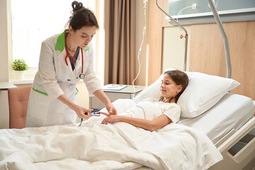 Fototapeta premium Woman doctor bent over the child in clinic