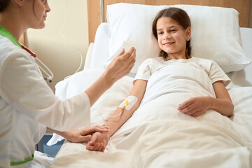 Fototapeta premium Doctor shows the girl a small medical container