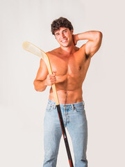 Handsome young man shirtless with hockey stick in hands