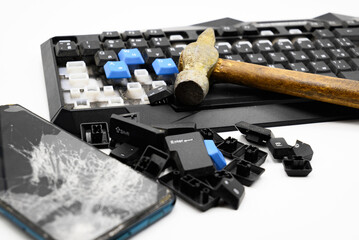 broken keyboard and a broken smartphone smashed with an iron hammer lie on a white background.