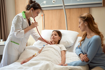 Doctor listens to thoracic region of the girl with statoscope