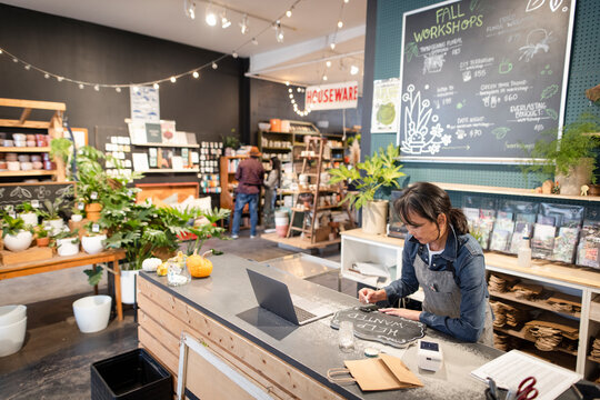 Female Business Owner Writing Help Wanted Sign In Garden Shop