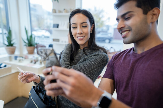 Happy Couple With Smart Phone Shopping In Boutique