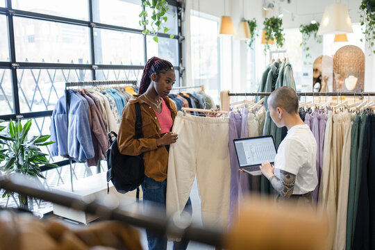 Female Business Owner Helping Customer Shopping For Sweatpants