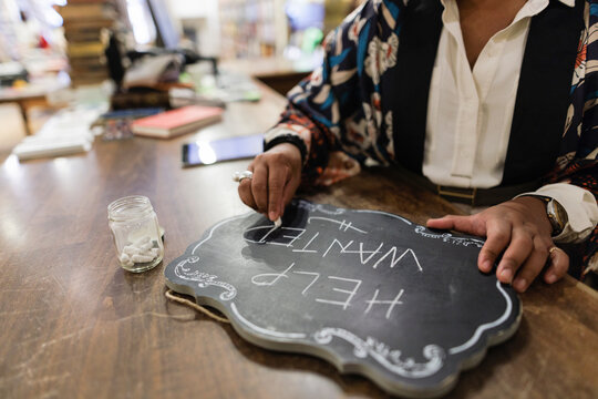 Close Up Business Owner Writing Help Wanted Sign In Bookshop