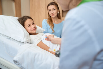 Obraz premium Doctor and mother are sitting at bedside of teenager girl