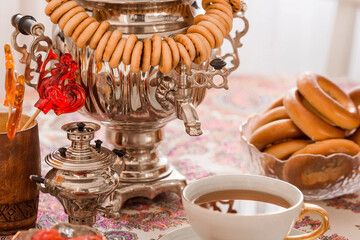 Russian traditions. Tea drinking with a samovar. Still life with a cup of tea, bagels, dried fruits, apple jam, caramel cockerel and Russian samovars.