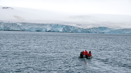 Zodiac inflatable boat navigating in front of a glacier at Kinnes Cove, Joinville Island, Antarctica