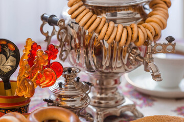 Russian traditions. Tea drinking with a samovar. Still life with a cup of tea, bagels, dried fruits, apple jam, caramel cockerel and Russian samovars.