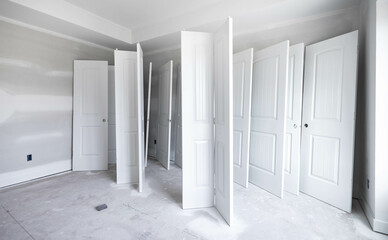 White painted on wood doors waiting to dry in an empty room for new build house at construction site, interior work. Home renovation, real estate business, commercial property project concept.