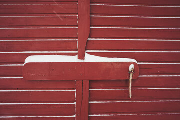 detail of red wooden gate while snowing