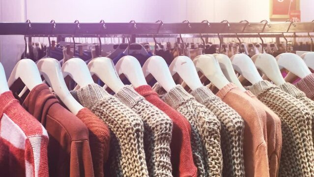 Women's textile and knitted woolen pullovers hang on hangers in a clothing store