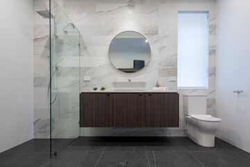 modern interior of new bathroom with shower, vanity, stylish tiles and toilet