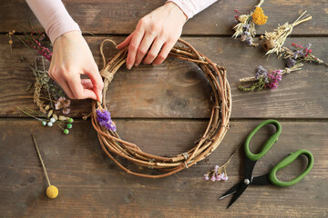 Florist at work: woman shows how to make a door wreath with dry flowers and orher plants. Step by...