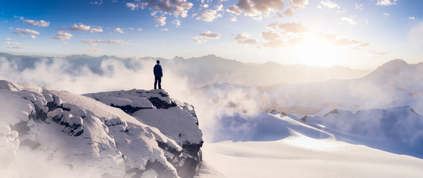 Adventurous Man Hiker standing on top of icy peak with rocky mountains in background. Adventure Composite. 3d Rendering rocks. Aerial Image of landscape from BC, Canada. Sunset Sky