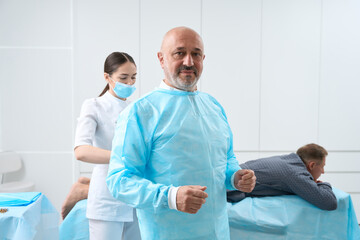 Nurse helps the surgeon in preparation for the operation