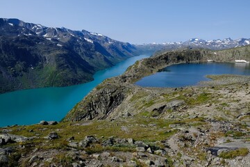 Obraz premium Scenic Besseggen trail in Jotunheimen, Norway - the most beautiful trekking trail in Norway. Silhouettes of hiking tourists on trail.