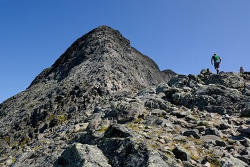 Fototapeta premium Scenic Besseggen trail in Jotunheimen, Norway - the most beautiful trekking trail in Norway. Silhouettes of hiking tourists on trail.