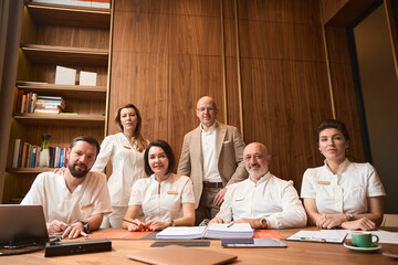 Men and women in overalls sit at a large table