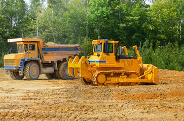 Obraz na płótnie Canvas Crawler dozer working on construction site or quarry. Mining machinery moving clay, smoothing gravel surface for new road. Earthmoving, excavations, digging on soils