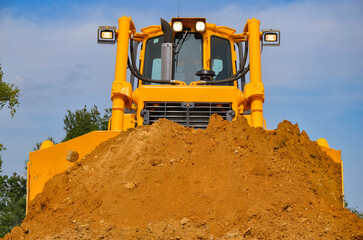 Crawler dozer working on construction site or quarry. Mining machinery moving clay, smoothing gravel surface for new road. Earthmoving, excavations, digging on soils