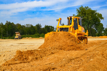 Crawler dozer working on construction site or quarry. Mining machinery moving clay, smoothing gravel surface for new road. Earthmoving, excavations, digging on soils