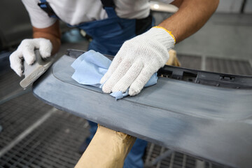 Mechanic cleaning car parts before painting in garage